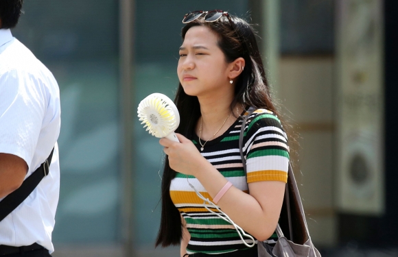 En kvinne i Tokyo forsøker å kjøle seg ned med en håndholdt vifte under hetebølgen. Mandag ble det satt ny varmerekord i Japan med 41,1 grader. 