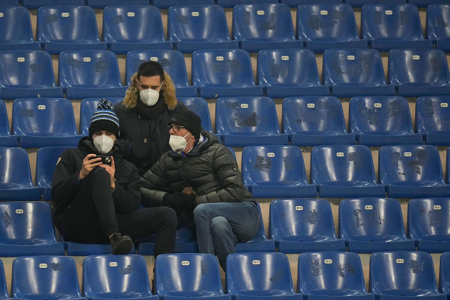 Bruken av filtrerende halvmasker av typen FFP2, her båret av tre fotballsupportere i Italia, blir mer og mer vanlig. FHI vil likevel fortsette å anbefale bruk av medisinske munnbind. 